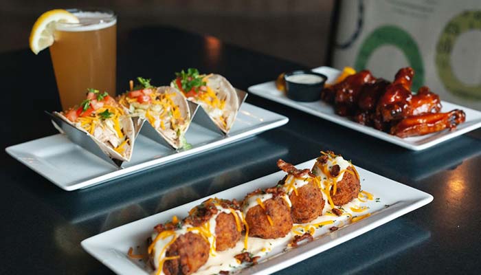 Four fried appetizers, tacos, sauced wings, and a beer at your favorite Bar & Grill table.