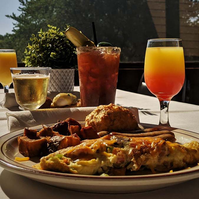Brunch food and drinks at Jacque B's Kitchen & Cocktails on a sunny table.