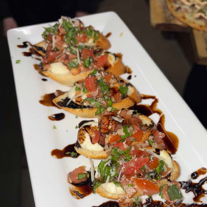 Four bruschetta with tomatoes, herbs, cheese, and glaze at Jacque B's Kitchen & Cocktails.