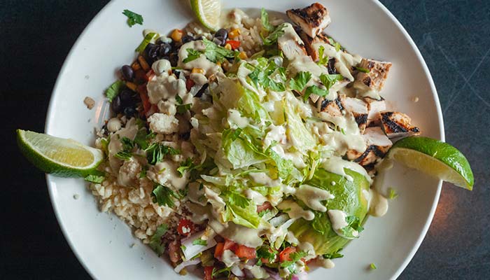 A Bar & Grill burrito bowl with grilled chicken, avocado, beans, rice, and creamy dressing.