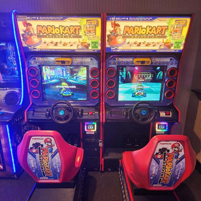 Two side-by-side Mario Kart arcade machines at the Bar & Grill, perfect with food and drink.